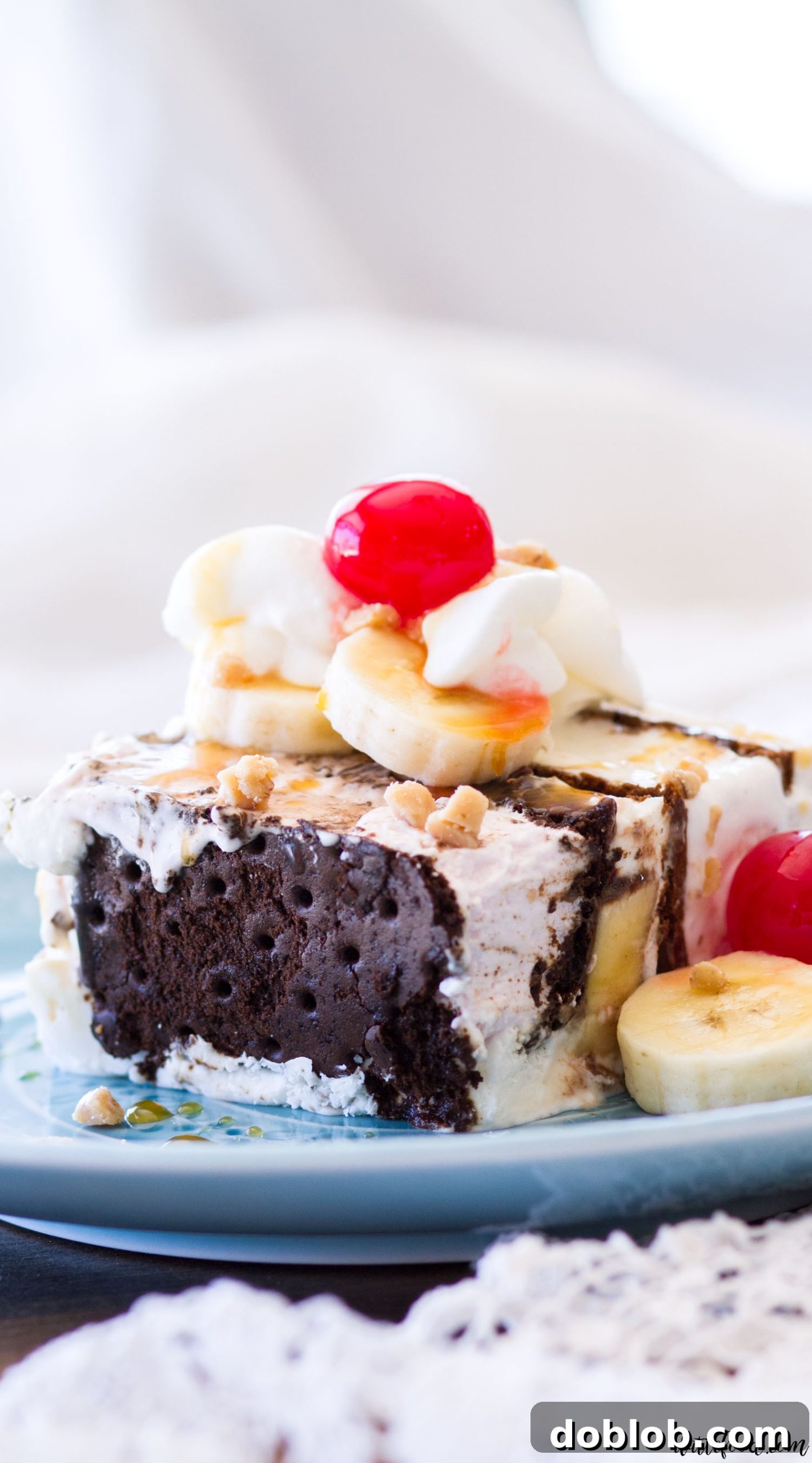 A generous slice of Banana Split Ice Cream Sandwich Cake on a plate, showcasing its layers and toppings.