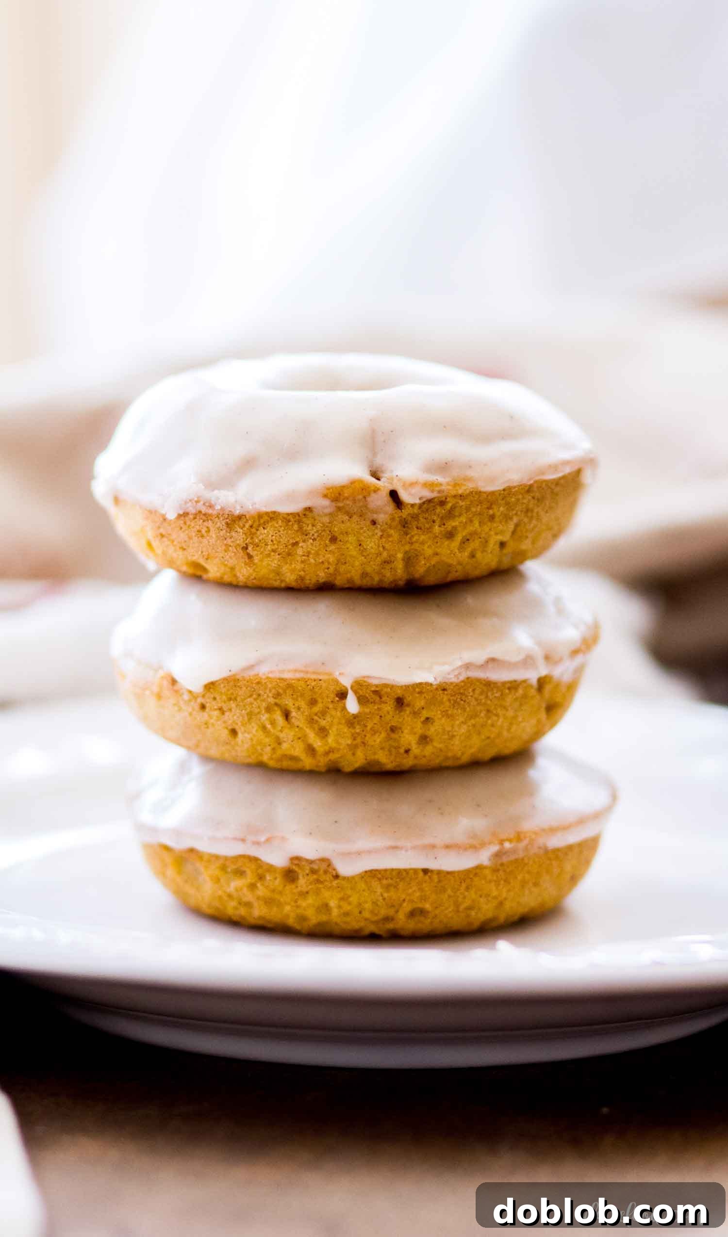 Perfectly Glazed Buttermilk Pumpkin Donuts A charming stack of several glazed pumpkin donuts, highlighting their beautiful golden-brown color and thick, sweet coating.