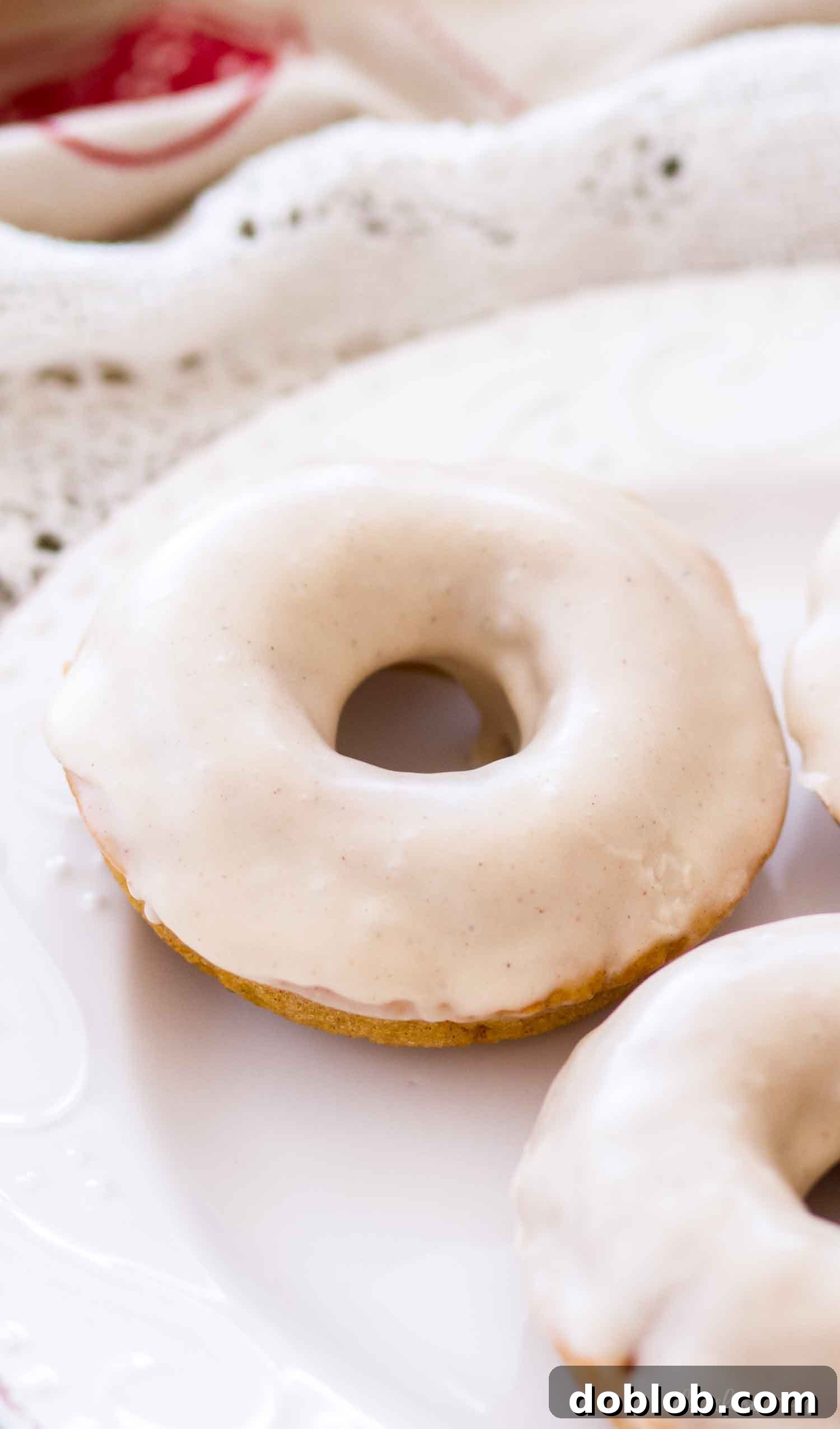 Homemade Buttermilk Pumpkin Donut with Maple Glaze A single baked buttermilk pumpkin donut with a generous maple glaze on a pristine white plate, ready to be enjoyed.
