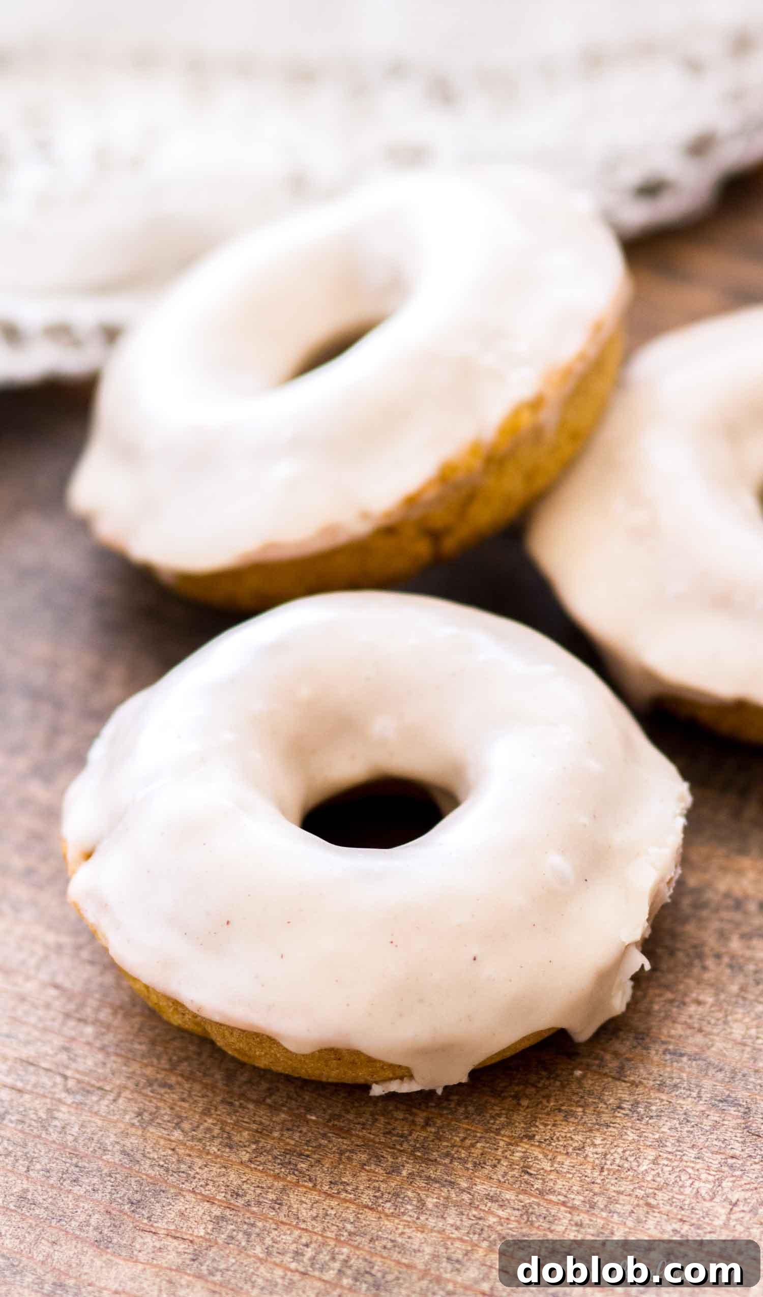 Baked Pumpkin Donut with Spiced Glaze A spiced pumpkin donut resting on a rustic brown cutting board, emphasizing its warm, inviting colors and texture.