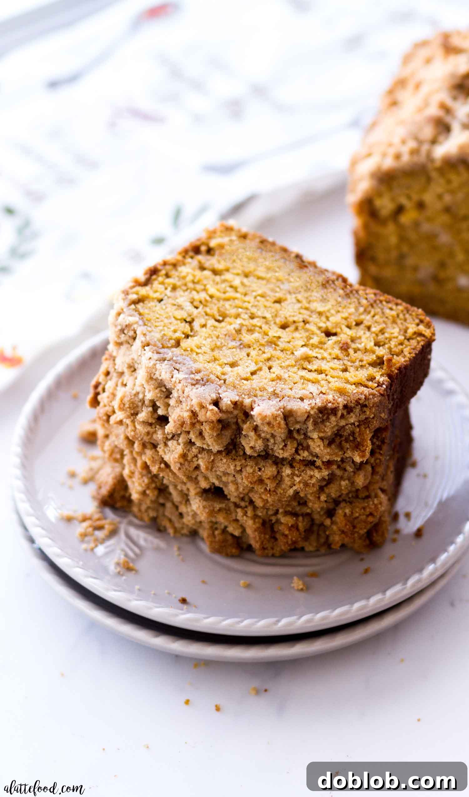Delicious Pumpkin Crumb Bread A slice of moist Easy Pumpkin Bread with a generous streusel crumb topping, served on a gray plate, showcasing its comforting texture.