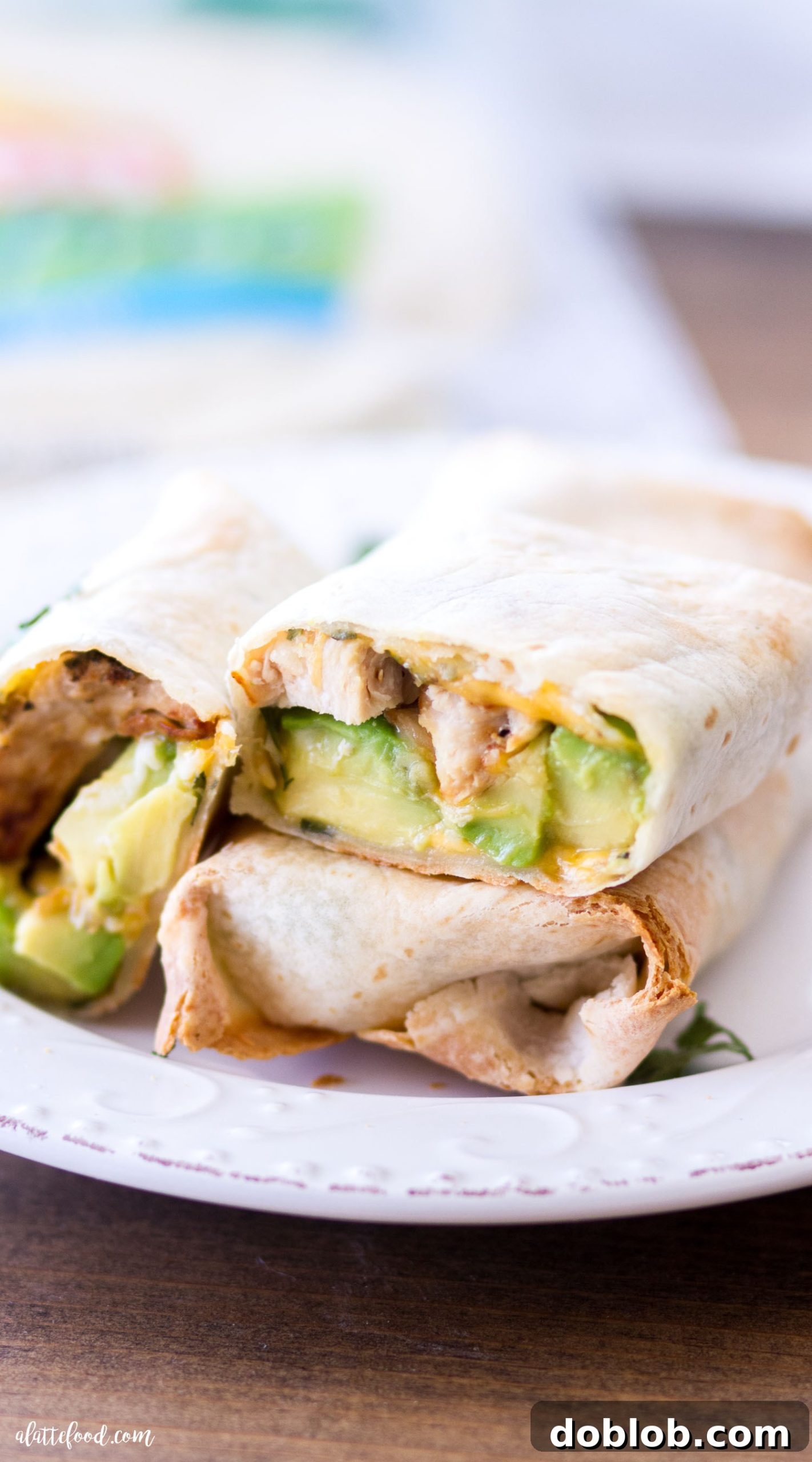 Hearty Oven-Baked Chicken & Avocado Burritos 7 A serving of a freshly baked Avocado Chicken Burrito on a plate, garnished with a dollop of sour cream and fresh cilantro.