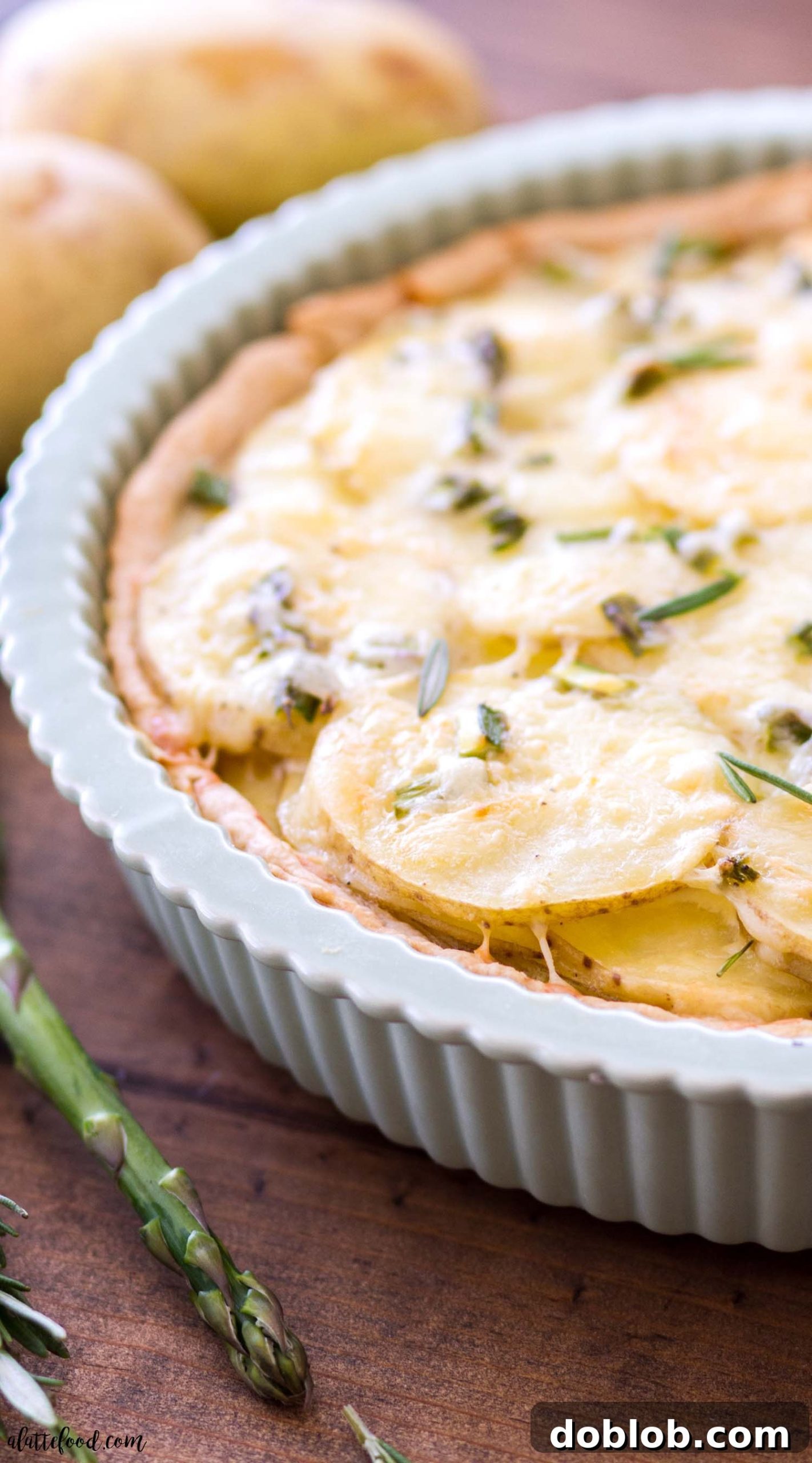 Closeup of a slice of Cheesy Asparagus Potato Tart with visible layers of potato, asparagus, and cheese.