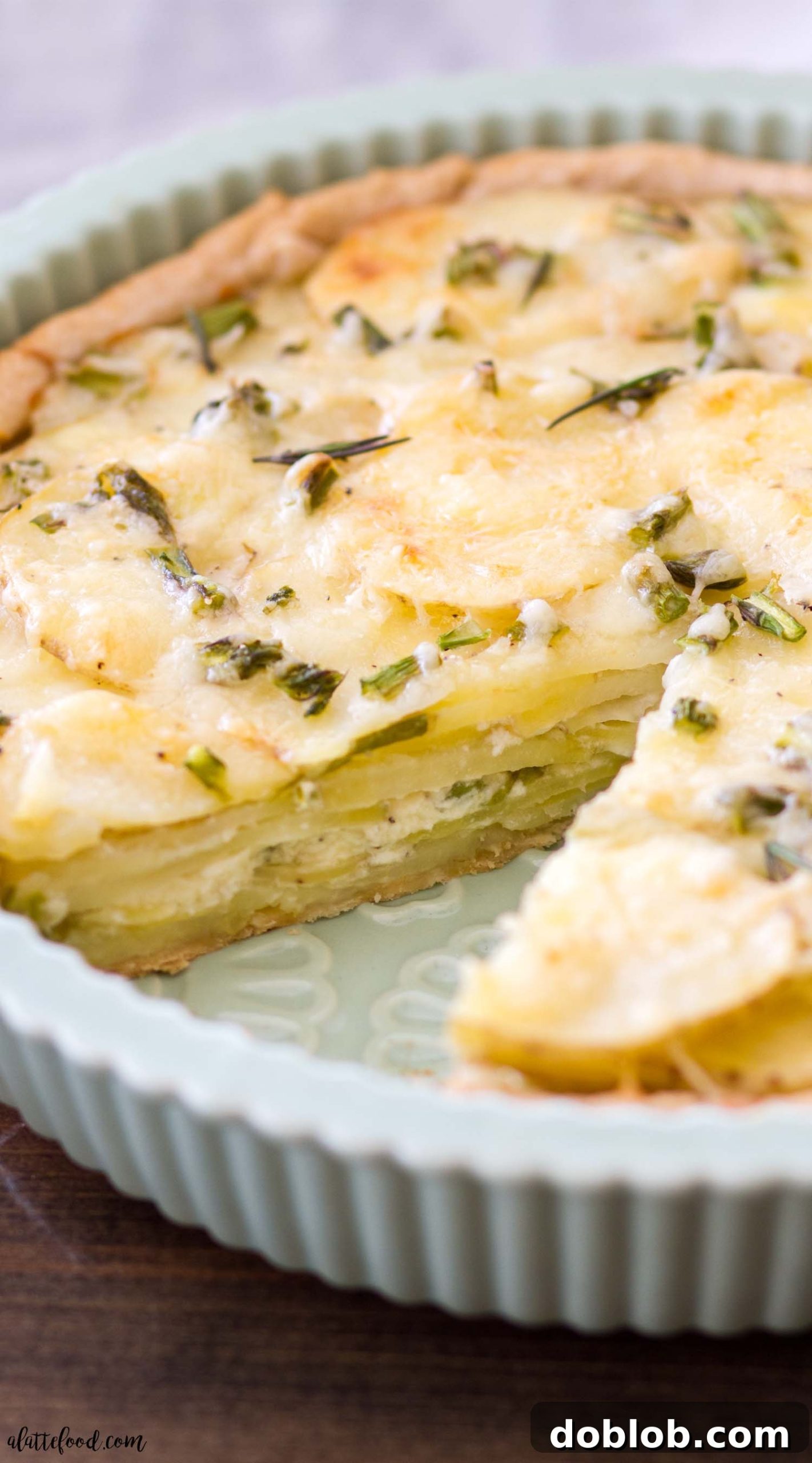 Slice of Cheesy Asparagus Potato Tart being lifted from the pan, showing the golden crust.