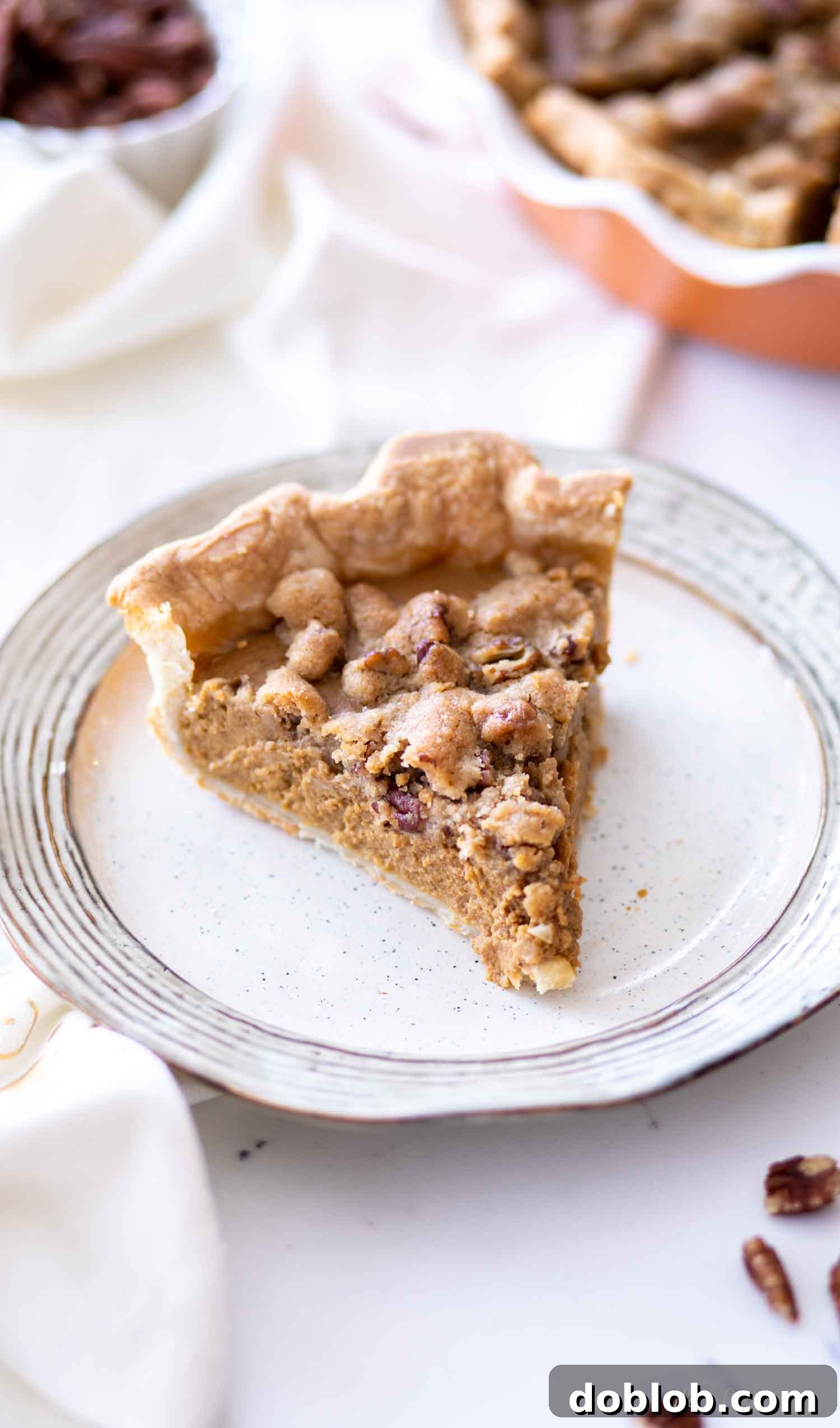 creamy pumpkin pie slice with whipped cream and chopped pecans on grey plate