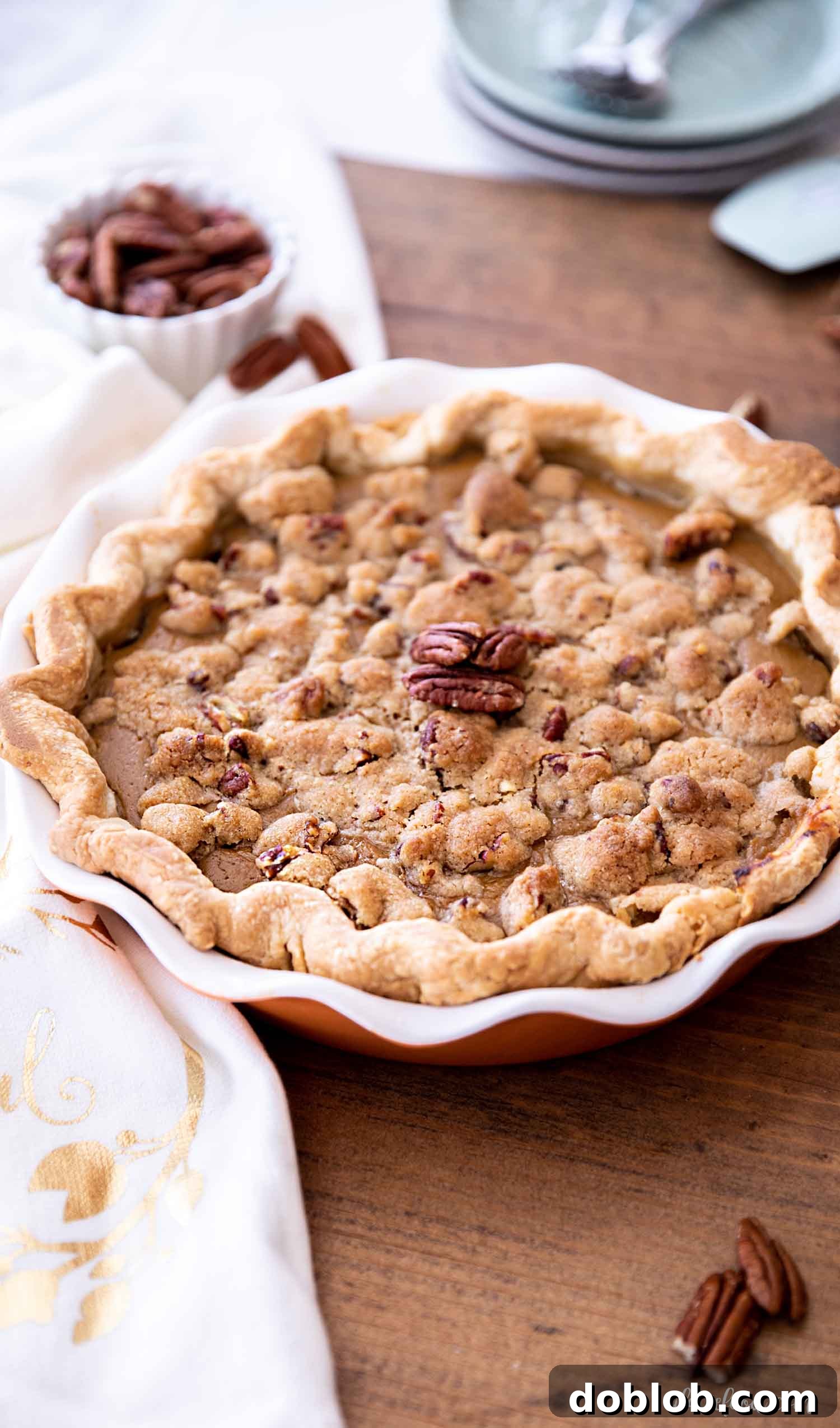 baked streusel topped apple butter pumpkin pie on wooden board