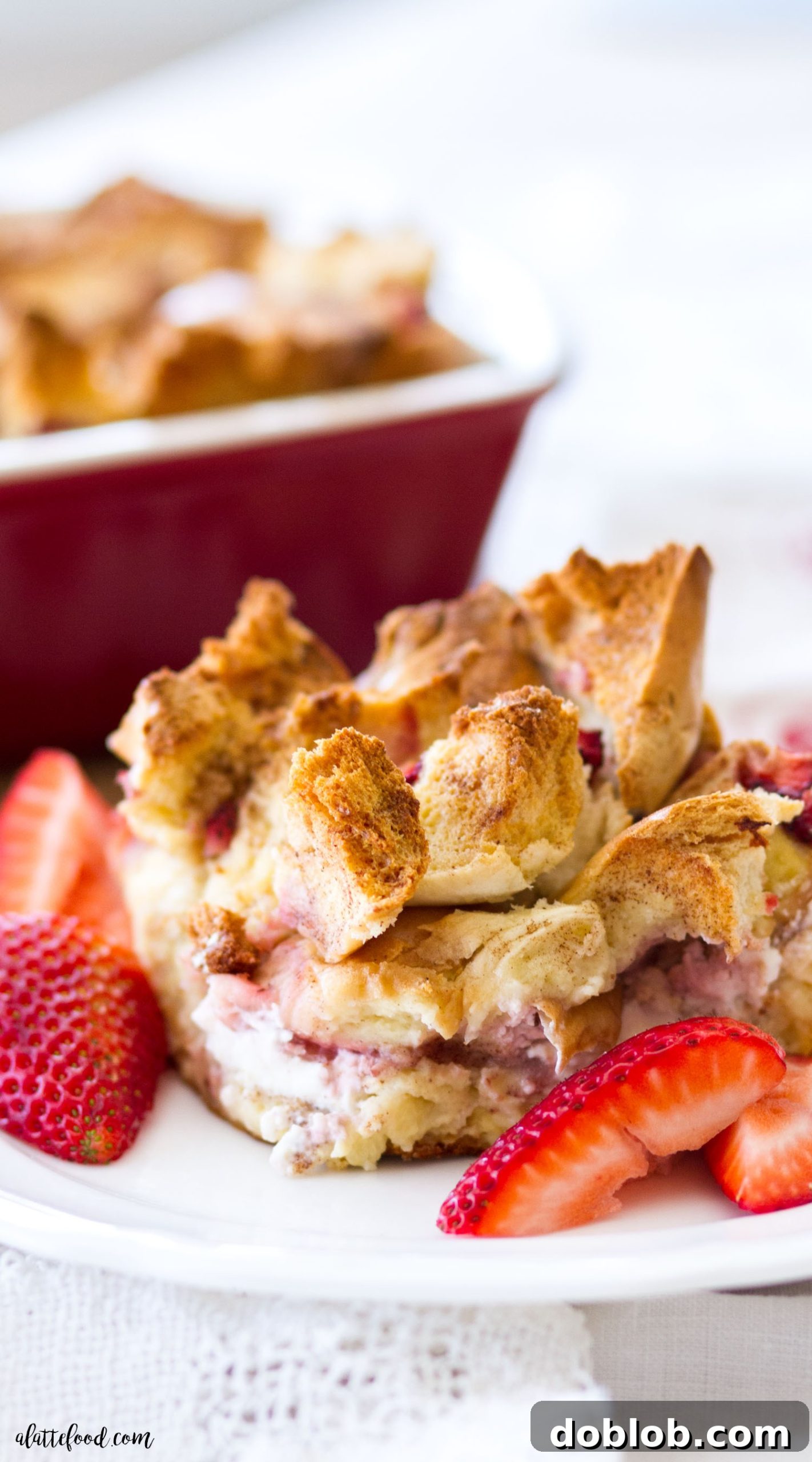 A delicious slice of Bagel and Cream Cheese Strawberry French Toast Casserole, garnished with fresh strawberries and a drizzle of maple syrup, ready to be served.