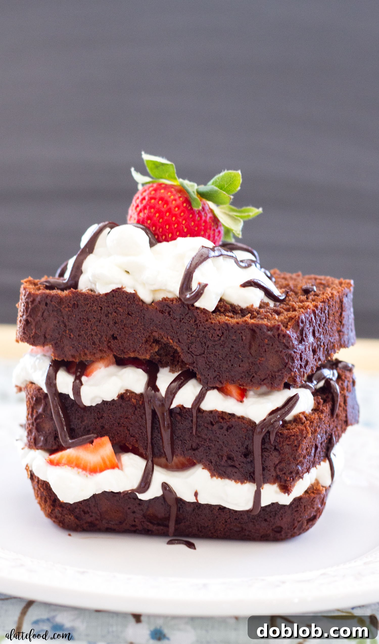A beautifully presented slice of chocolate espresso pound cake with various toppings on a dark background
