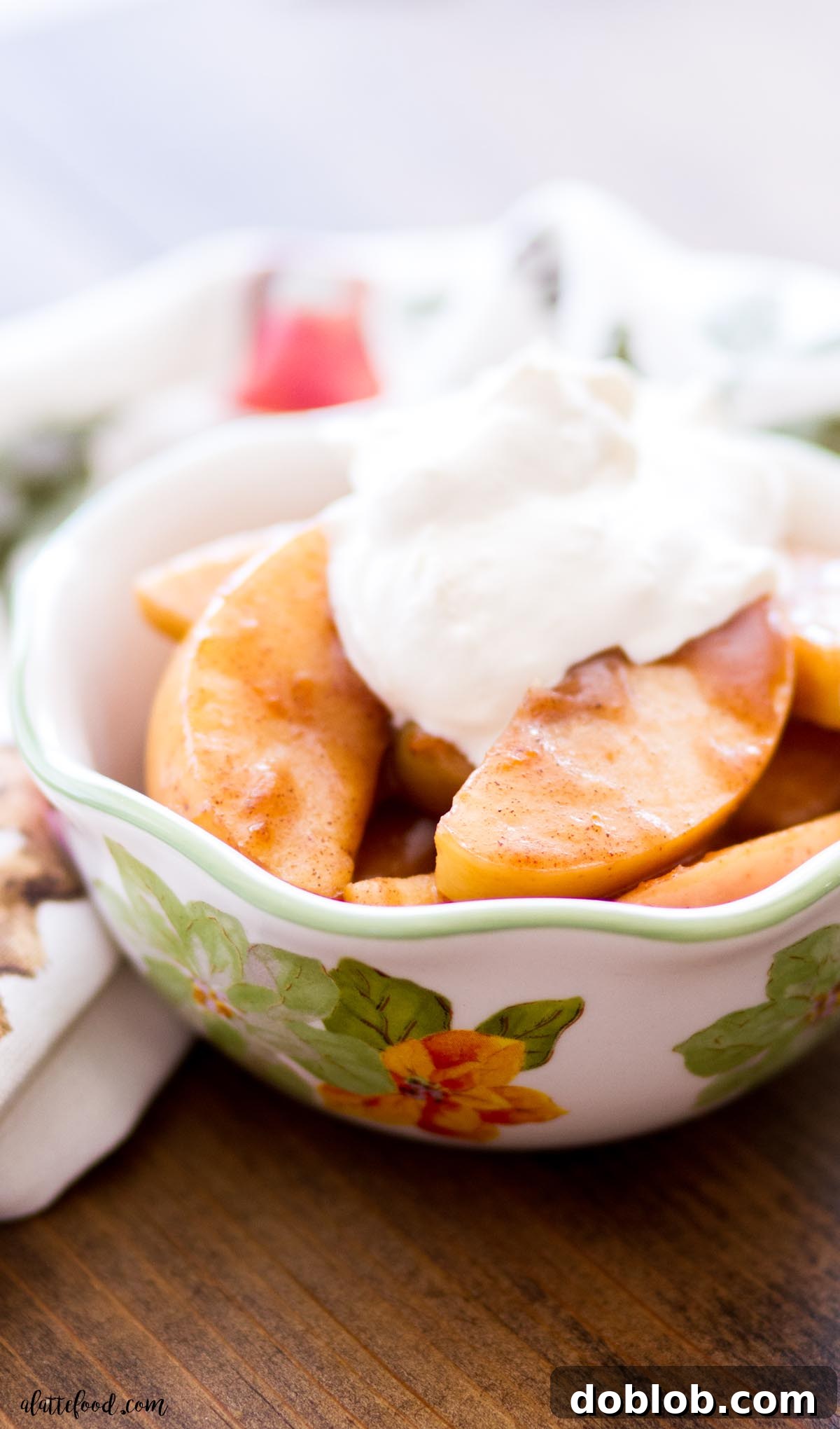 Spiced Cinnamon Apples in a white flowered bowl topped with whipped cream