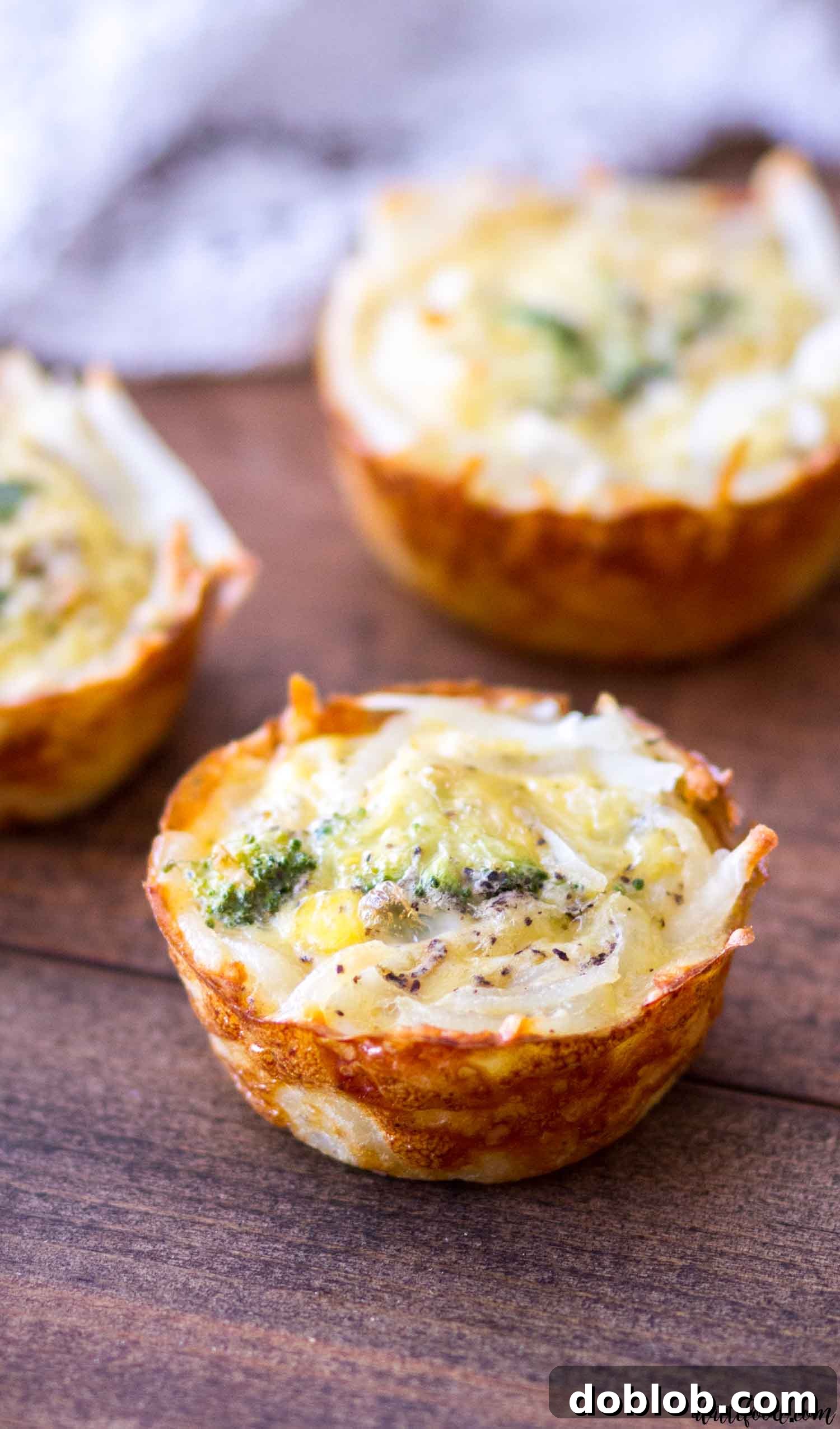 Golden brown hash brown crusted broccoli cheddar quiche cups arranged on a white plate, ready to be served