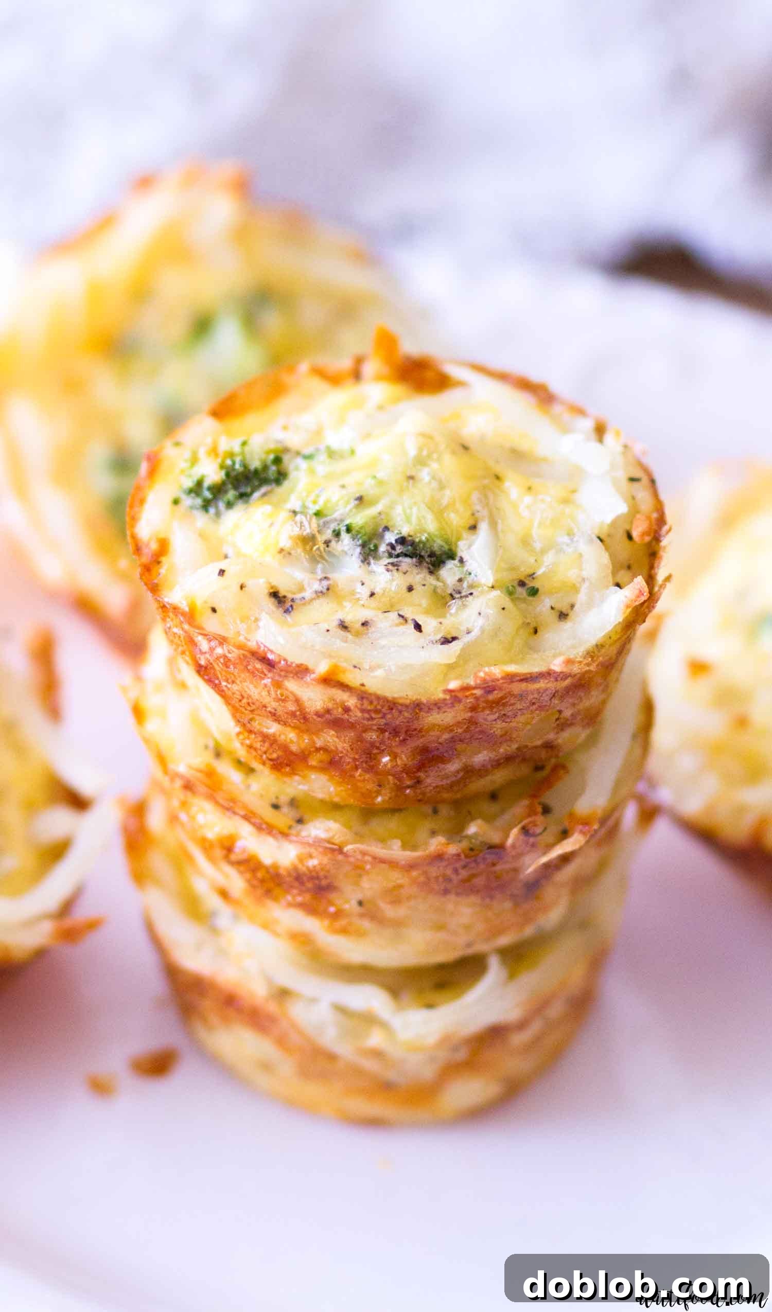 A dozen mini broccoli and cheddar quiche cups with hash brown crusts baked in a standard muffin tin