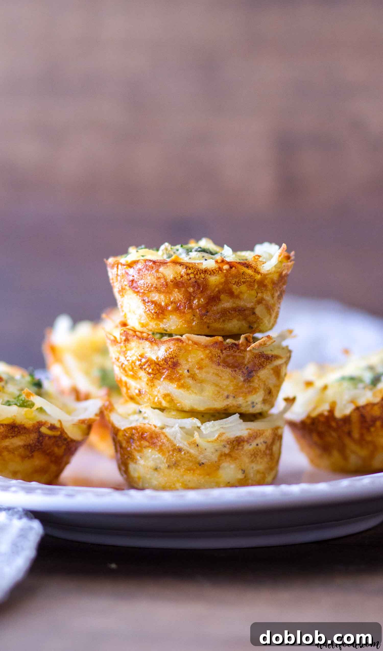 Two beautiful hash brown crusted quiche cups presented on a white plate, garnished with fresh herbs, ready for serving