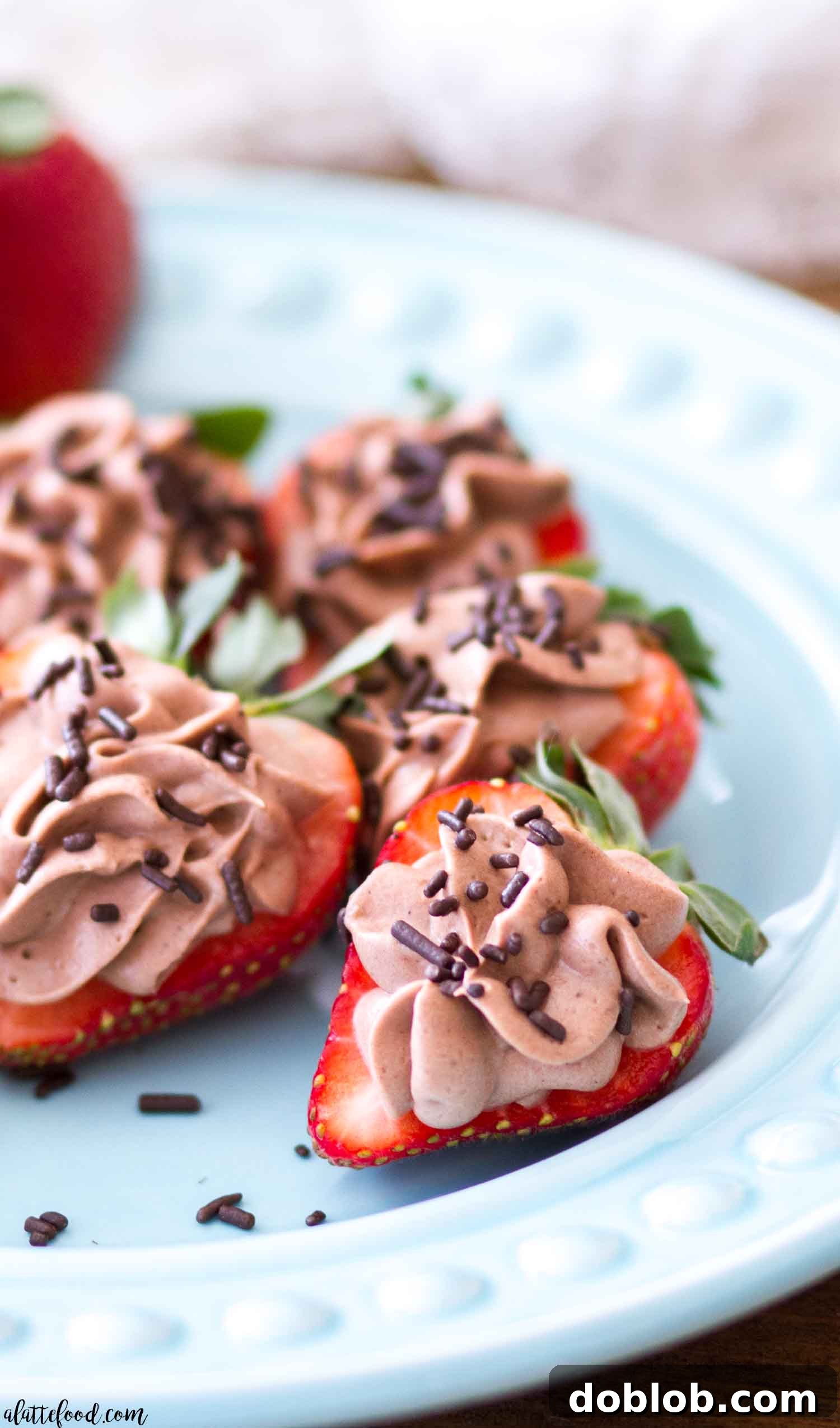 Chocolate Cheesecake Stuffed Strawberries Dessert A hand holds a single, delectable No Bake Chocolate Cheesecake Stuffed Strawberry with festive sprinkles.