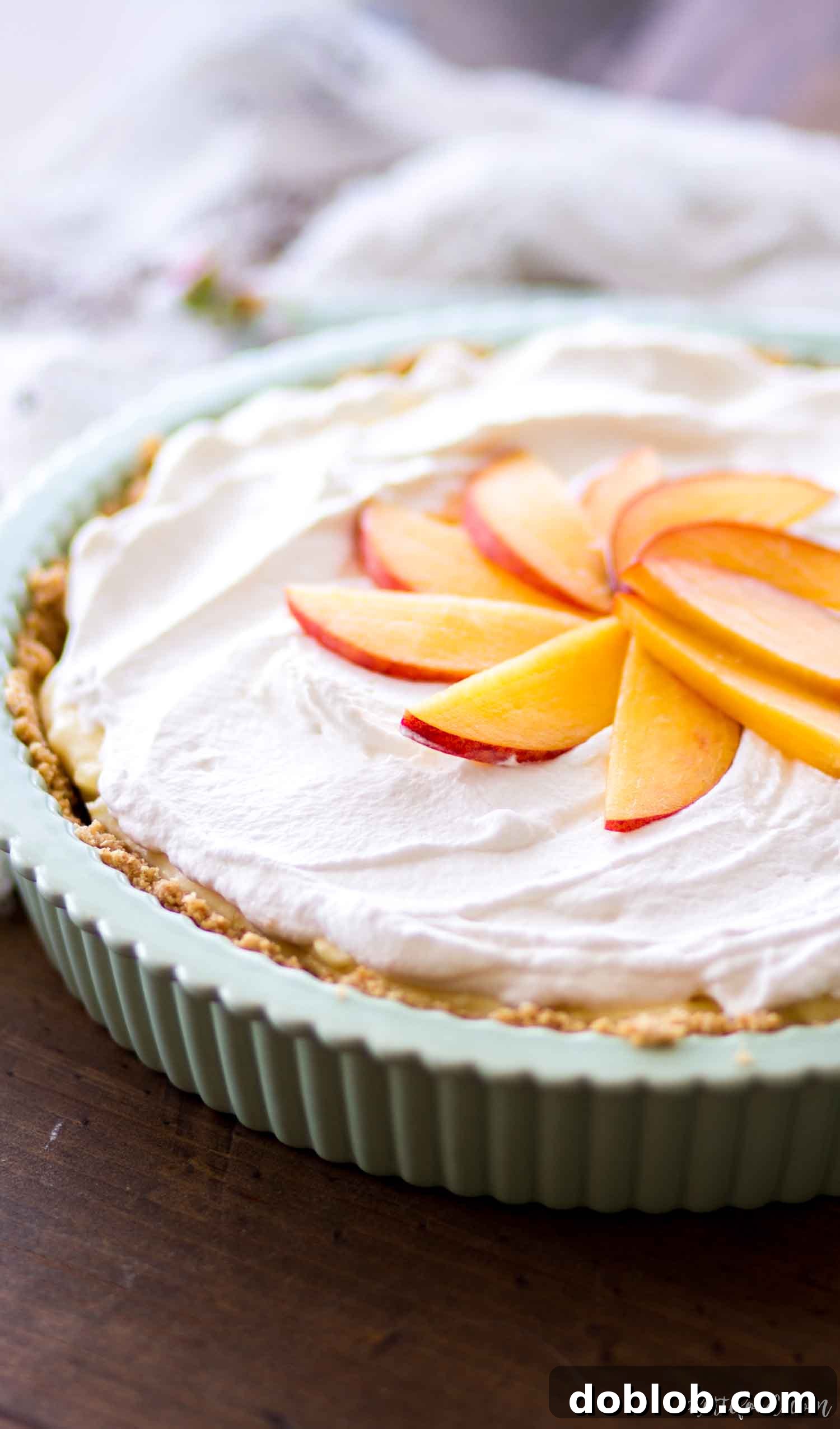 A vibrant No Bake Peach Cream Pie in a green dish, garnished with fluffy whipped cream and fresh peach slices, ready to be enjoyed.