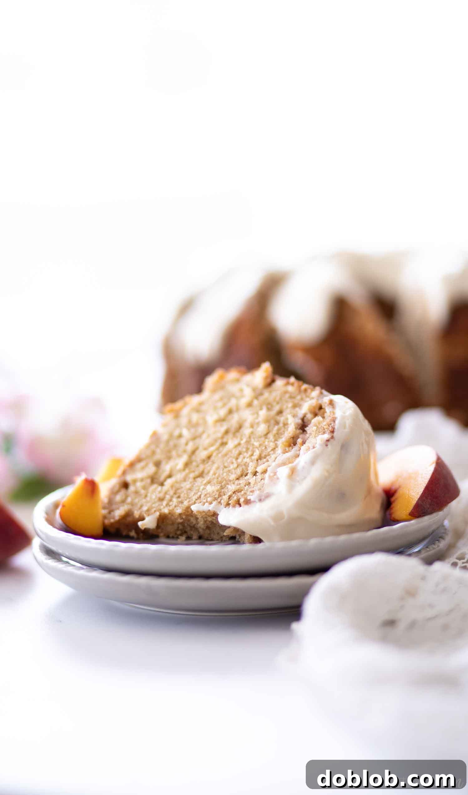 A generous slice of peach pound cake topped with cream cheese glaze on a grey plate.