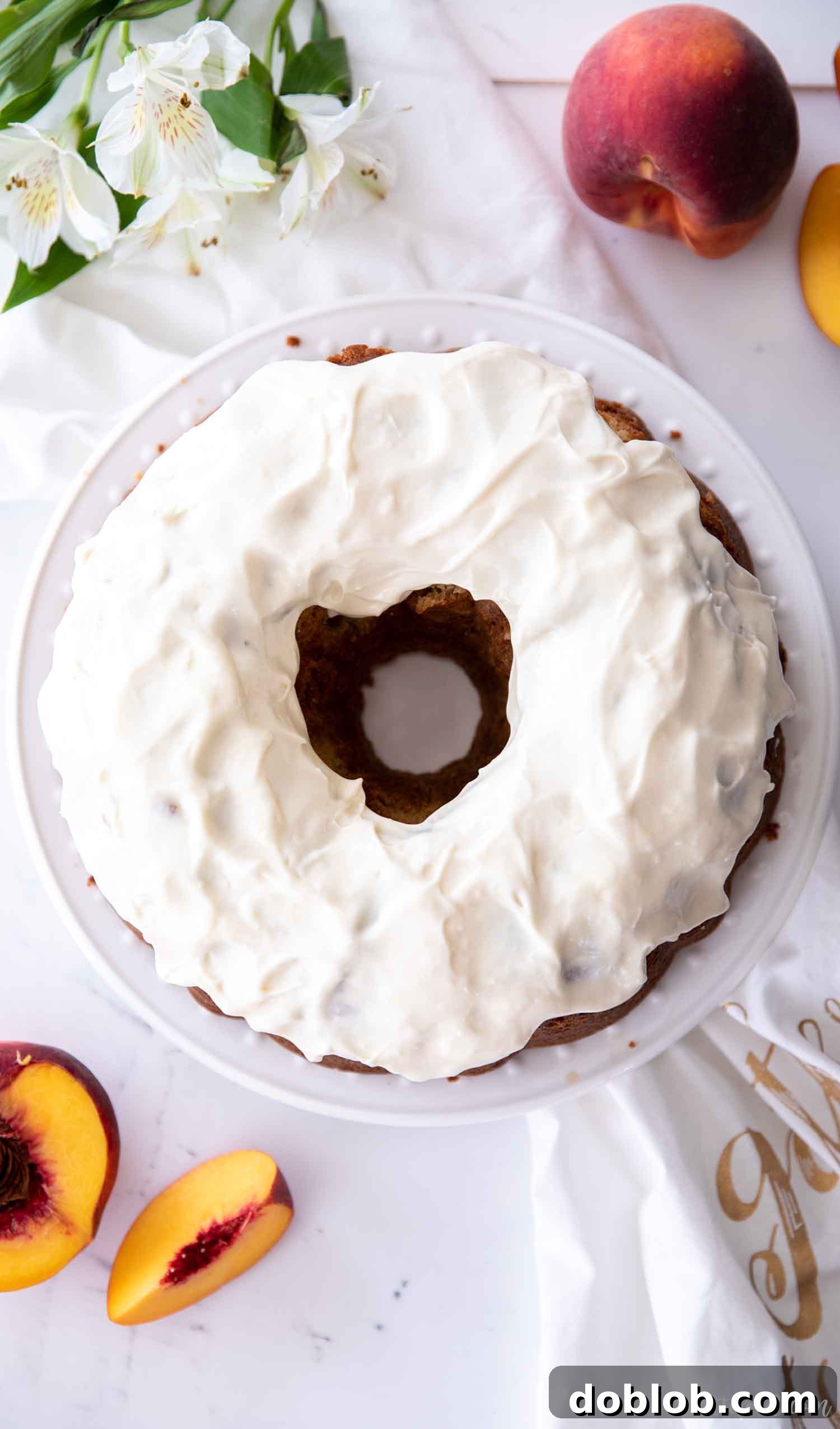 A beautiful cream cheese glazed peach pound cake on a white plate, ready to be sliced.