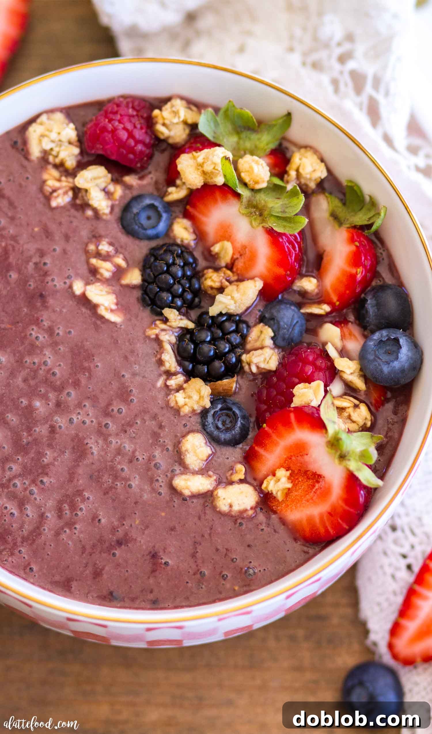 Homemade Açaí bowl adorned with a vibrant array of toppings, including perfectly sliced strawberries, fresh blueberries, and a sprinkle of wholesome granola, all resting on a thick, dark purple Açaí base. The image emphasizes freshness and customization. Keywords: homemade Acai bowl, healthy breakfast, customizable, gluten free, refined sugar free, easy recipe.