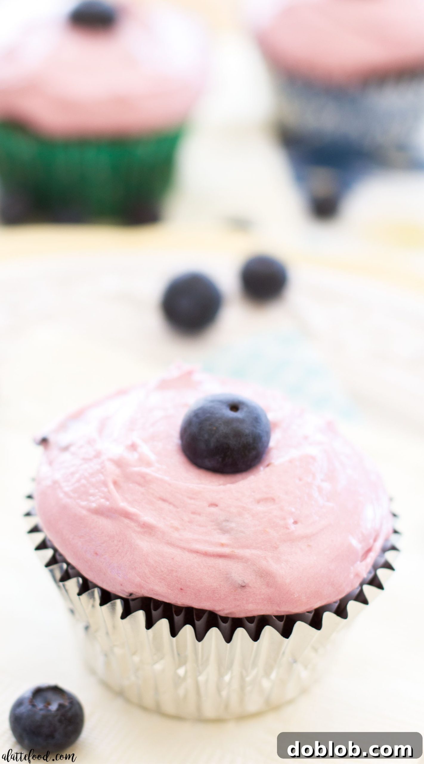 Pile of milk chocolate cupcakes topped with blueberry frosting