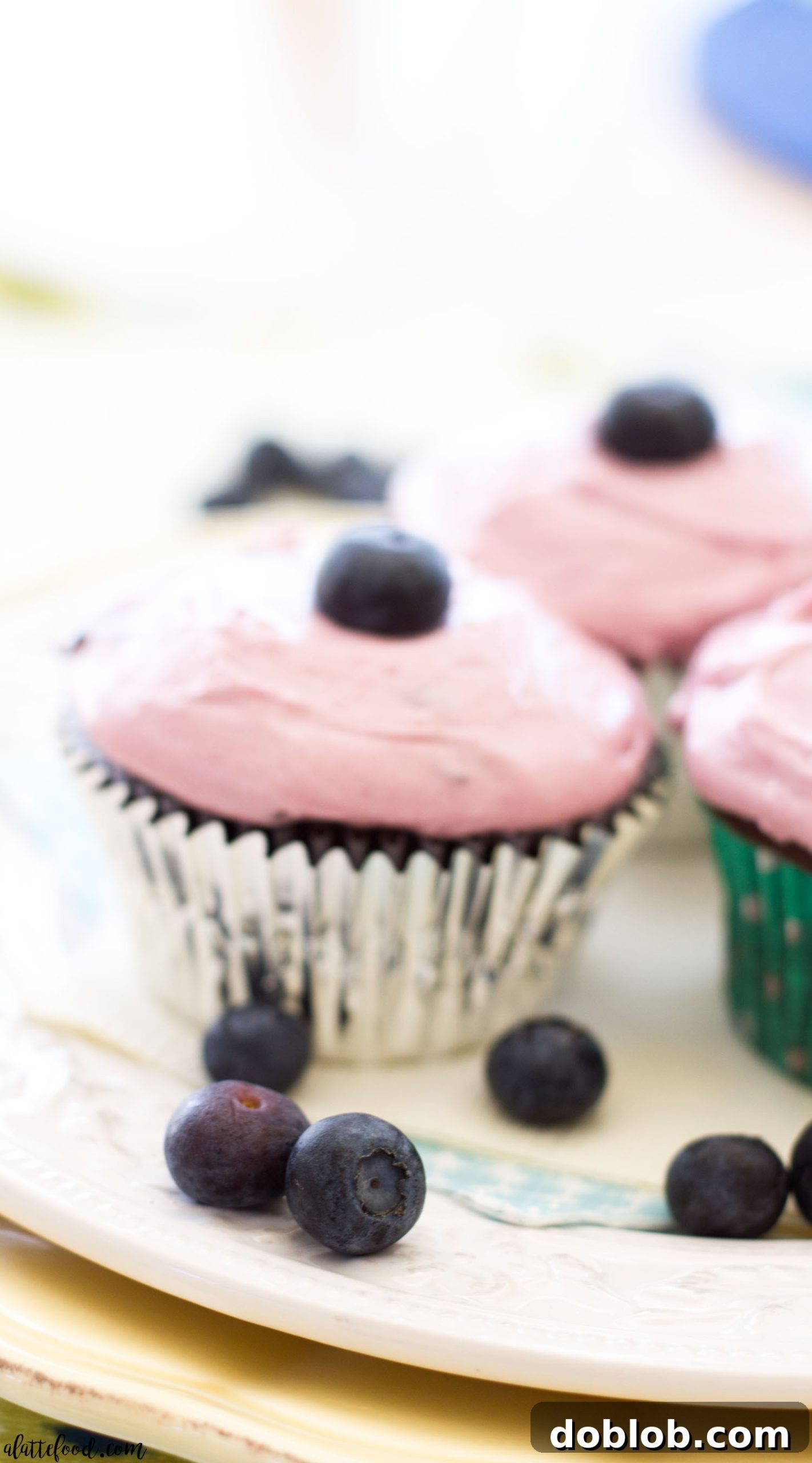 Single milk chocolate cupcake with fluffy blueberry frosting on a plate