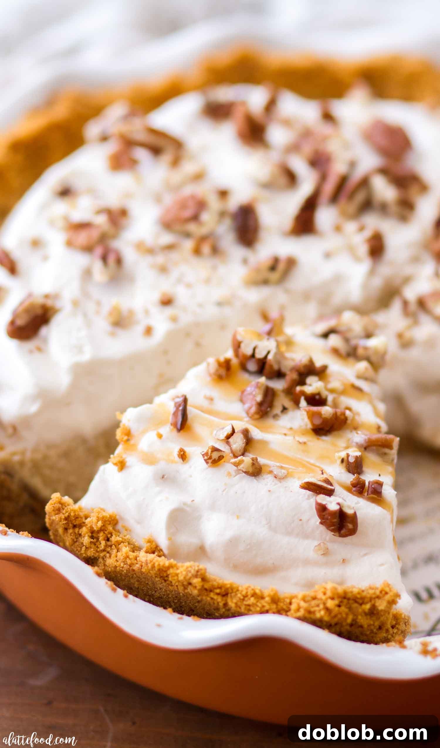 A slice of Pecan Caramel Cheesecake with homemade caramel whipped cream and chopped pecans.